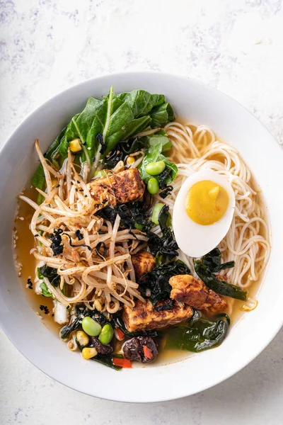 Asian fusion vegan meat-free ramen noodles with mushrooms, fermented tofu, sprout, beans, vegan egg and green pak choi leaves