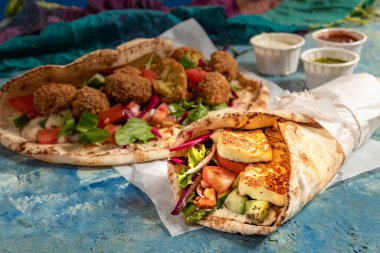Traditional Mediterranean Arabic grilled halloumi and falafel, hummus and vegetables in flatbread wraps with herbs and a variety of sauces