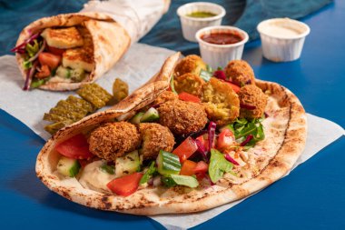Traditional Mediterranean Arabic grilled halloumi and falafel, hummus and vegetables in flatbread wraps with herbs and a variety of sauces