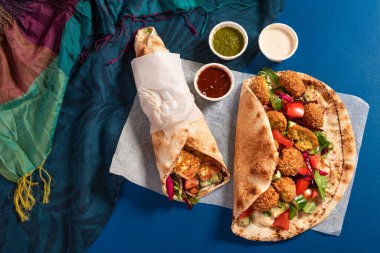 Traditional Mediterranean Arabic grilled halloumi and falafel, hummus and vegetables in flatbread wraps with herbs and a variety of sauces