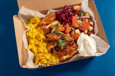 Geleneksel Doğu Akdeniz yemeği ızgara tavuk, sarı pirinç, taze salata ve karton ambalajda yoğurt.
