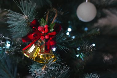 Noel ağacında asılı iki altın çan ve kırmızı bir kurdele olan bir Noel süsü.