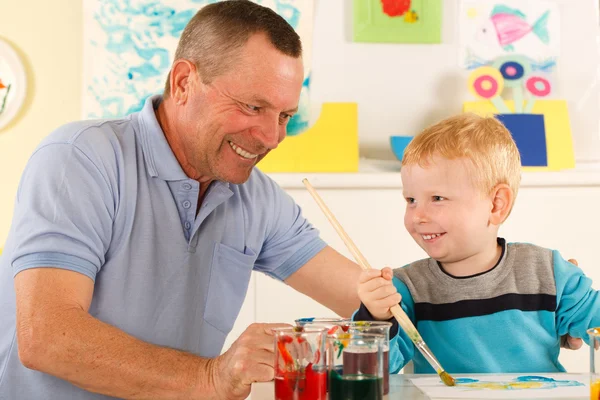 Child paints with a smile on his face — Stock Photo, Image
