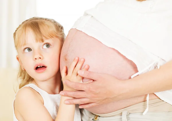 Meisje gevoel van haar moeder zwangere buik. — Stockfoto
