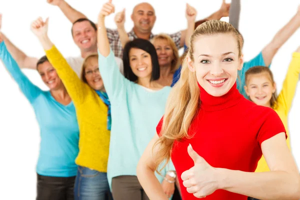 Smiling girl with thumbs up with large group of people on backgr — Stock Photo, Image