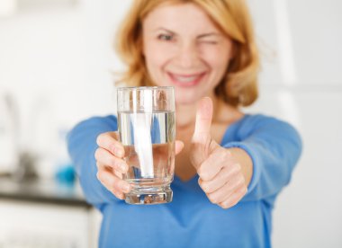 bir bardak su tutarak ve gösterilen kadın thumbs-up
