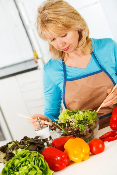 Mujer preparando ensalada en la cocina. — Foto de Stock