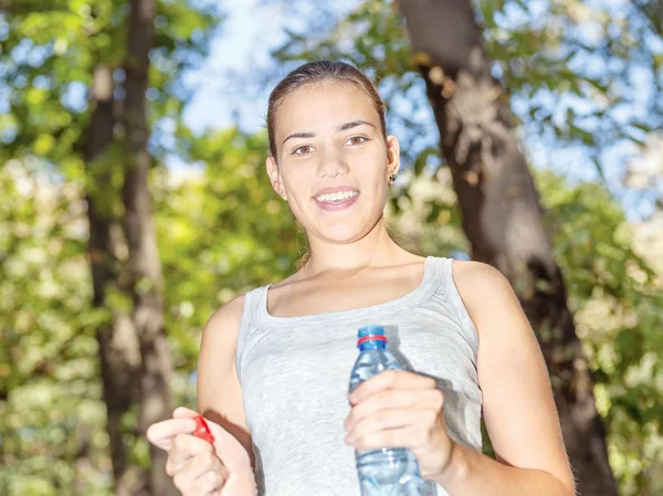 Happy girl in forest holding bottle of water — Stock Photo, Image