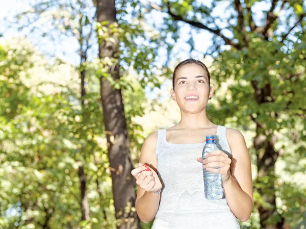 Ευτυχισμένος κορίτσι στο δάσος, κρατώντας το μπουκάλι του νερού — Φωτογραφία Αρχείου