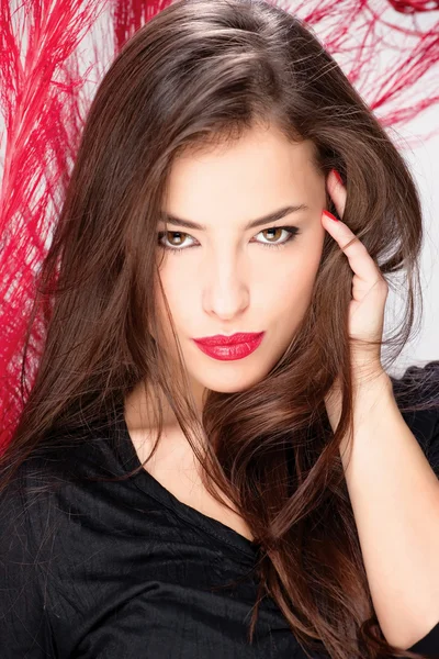 Woman with long hair in front of red feather — Stock Photo, Image