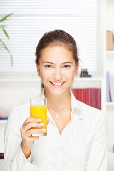 Jovem mulher sorridente segurando vidro de suco de laranja — Fotografia de Stock