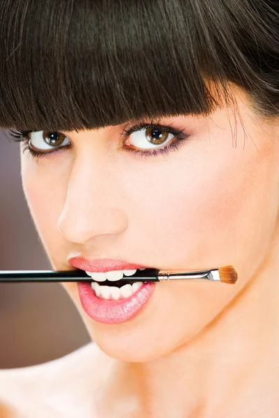 Mujer mantenga maquillaje cepillo entre dientes —  Fotos de Stock