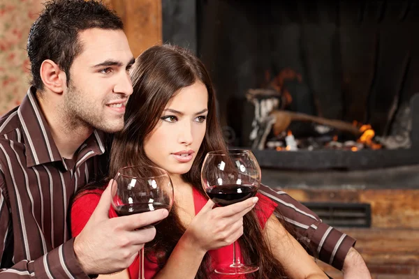 Casal desfrutando de vinho perto da lareira — Fotografia de Stock