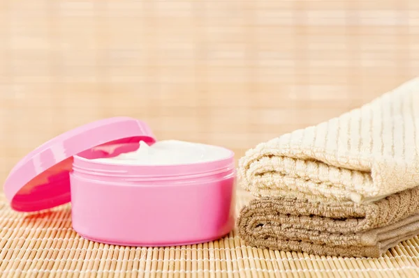 Creme in rosa Tasse mit Handtüchern — Stockfoto