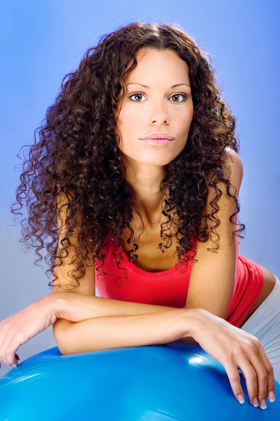 Hübsche Locken Haare Frauen auf blauen Pilates Ball — Stockfoto