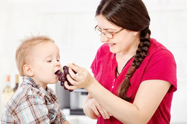 Mother feeding child with grape — Stock Photo, Image