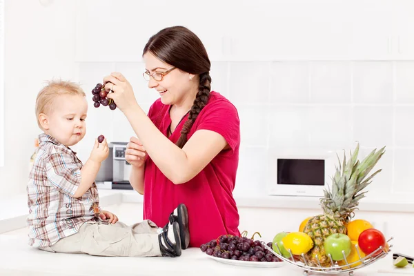 Moeder voeding kind in keuken — Stockfoto