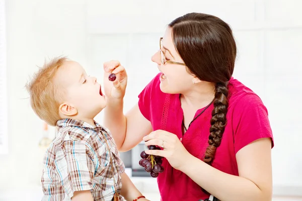 Mother feeding child with grapes — Stock Photo, Image