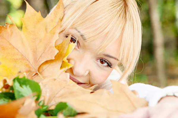 Jeune blonde derrière les feuilles — Photo