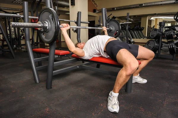 Ung man gör bänk press träning i gym — Stockfoto
