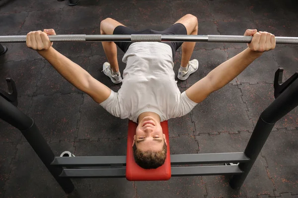 Ung man gör bänk press träning i gym — Stockfoto