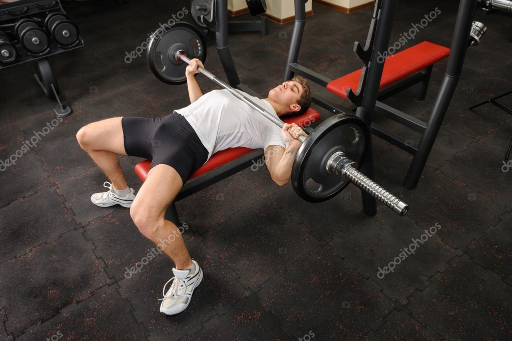 Young man doing bench press workout in gym Stock Photo by ©starush 41215469