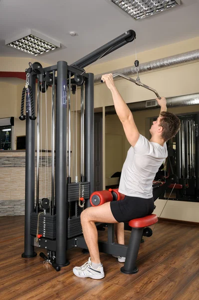 Hombre joven haciendo lats pull-down entrenamiento en el gimnasio —  Fotos de Stock