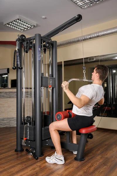 Young man doing lats pull-down workout in gym — Stock Photo, Image