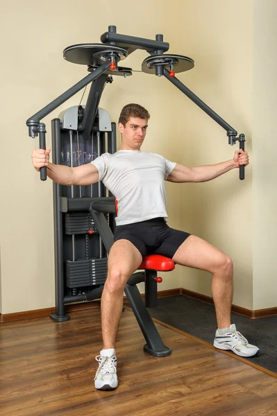 젊은 남자는 체육관에서 가슴 비행 기계에서 운동 — 스톡 사진