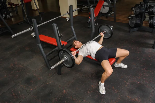 Joven haciendo ejercicio de la prensa del banco en el gimnasio —  Fotos de Stock