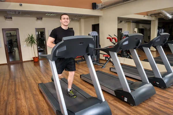 Young man running at treadmill in gym — Stock Photo, Image
