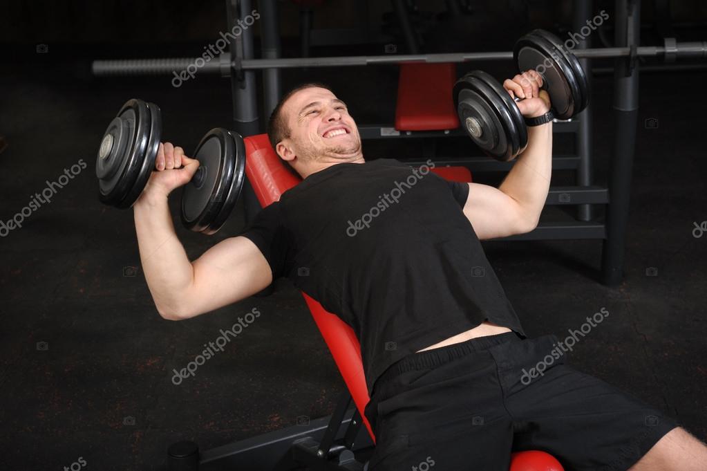 Young Man Doing Dumbbell Incline Bench Press Workout In Gym