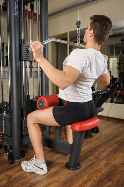 Hombre joven haciendo lats pull-down entrenamiento en el gimnasio —  Fotos de Stock