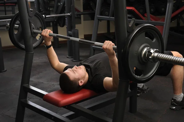 Joven haciendo ejercicio de la prensa del banco en el gimnasio —  Fotos de Stock