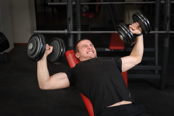 Jovem fazendo Dumbbell Incline Bench Press treino no ginásio — Fotografia de Stock