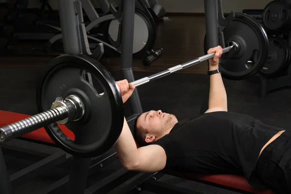 Young man doing bench press workout in gym — Stock Photo, Image
