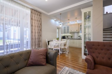 Büyük pencereli lüks stüdyo daire, oturma odasından beyaz büyük mutfağa ve yuvarlak yemek masasına manzara