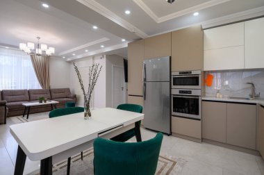 Modern klasik beyaz ve bej renkli lüks mutfak stüdyo dairesinin içinde yemek odası var.