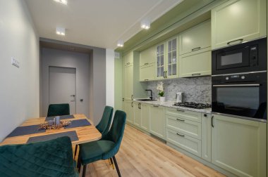 Modern moda açık yeşil lüks mutfak, yemek masası ve koyu yeşil sandalyeler.