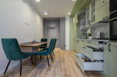 Modern trend açık yeşil lüks mutfak, yemek masası ve koyu yeşil sandalyeler, bazı çekmeceler geri çekilir