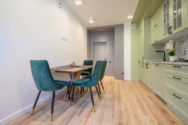 Modern moda açık yeşil lüks mutfak, yemek masası ve koyu yeşil sandalyeler.