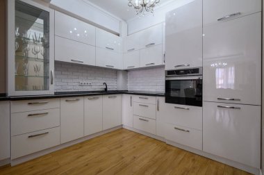 Stüdyo dairede siyah atölyesi olan beyaz, modern mutfak mobilyalarına yakın çekim.