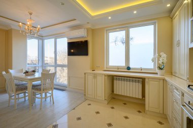 Klasik beyaz ve bej renkli lüks mutfak. Stüdyo daire içinde yemek masası var.