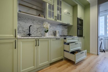 Modern trend açık yeşil lüks mutfak, yemek masası ve koyu yeşil sandalyeler, bazı çekmeceler geri çekilir