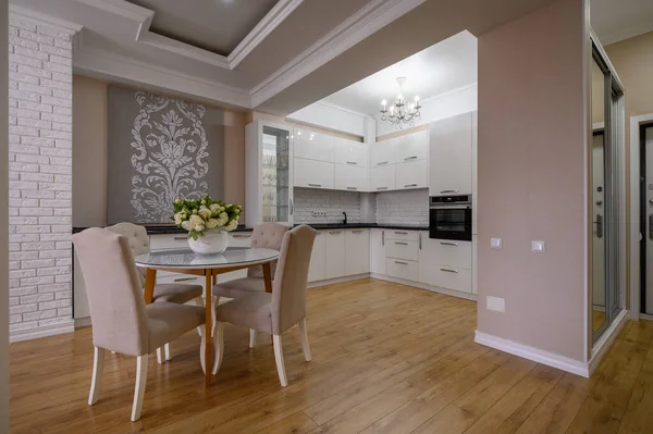 Luxury white modern kitchen with pink and white walls and laminated wooden flooring in studio apartment