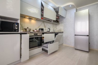 Interior of well designed modern trendy white kitchen, drawers retracted