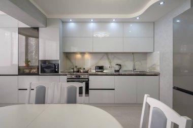Interior of well designed modern trendy white kitchen, front view