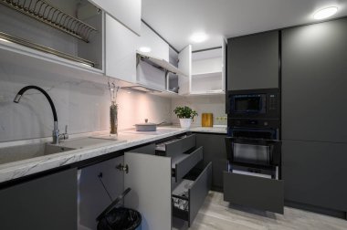 Closeup details of showcase interior of modern simple trendy dark grey and white kitchen, drawers retracted