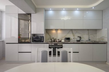 Interior of well designed modern trendy white kitchen, front view