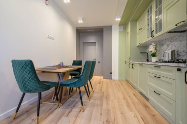 Modern moda açık yeşil lüks mutfak, yemek masası ve koyu yeşil sandalyeler.